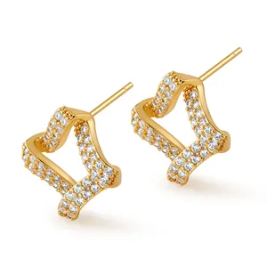Vista macro detallada de pendientes de botón de corazón irregular en oro con pavé de circonio