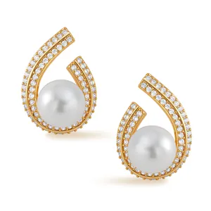 Detail of gold spiral earrings with pavé zircons and a central lustrous white pearl