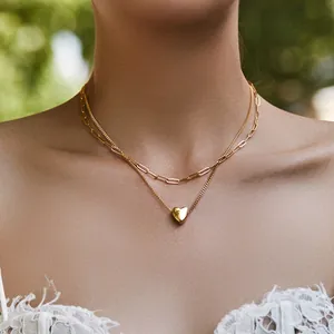 Close-up of double-layered gold paperclip chain necklace with a 3D heart pendant on model