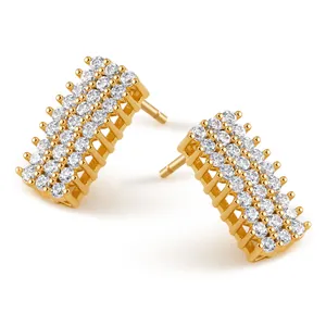 Detalle macro de pendientes curvos con triple fila de circonitas blancas y acabado oro de 18K
