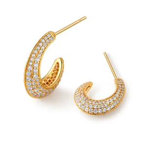 Detailed view of C-shaped gold earrings with micro-paved sparkling cubic zirconia crystals