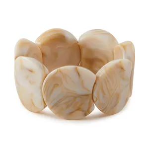 Détails de pièces en résine marbrée crème reliées par un cordon élastique de bracelet