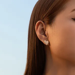 Elegant irregular heart stud earrings with pavé zircon setting worn by a female model