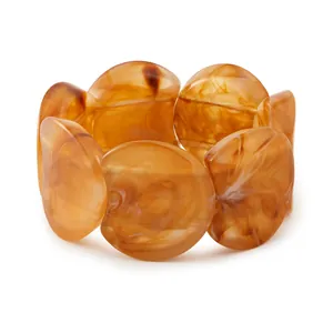 Détail des perles en acrylique texture marbre ambre sur un large bracelet élastique