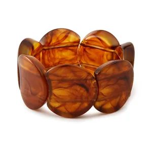 Détail d'un bracelet extensible en résine ambre écaillée avec des textures marbrées