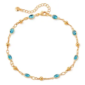 Close-up of gold beaded anklet featuring blue oval gemstones and lobster clasp detail