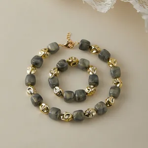 Dettaglio di un set di gioielli con perle in marmo grigio e sfere dorate irregolari