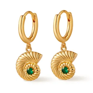 Detailed close-up of golden sea snail hoop earrings with sparkling green gemstones