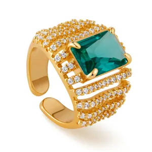 Detail of bohemian gold ring featuring a large emerald-cut green stone and zircon pavé