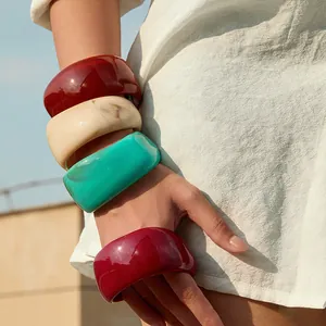 Close-up of four chunky colorful acrylic bangles worn together for a vintage look