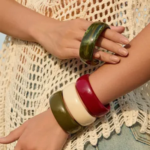 Detailed shot of chunky resin bangles in dark green, beige and burgundy marble texture