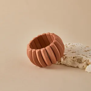Primer plano de pulsera de resina naranja con eslabones geométricos sobre piedra natural