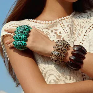 Dettaglio di bracciali elastici in acrilico con stampa leopardata blu e beige sul polso