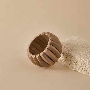Detalle de pulsera elástica de resina marrón sobre piedra y fondo beige suave