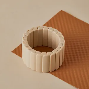 Gros plan sur un bracelet extensible en acrylique beige sur un fond caramel texturé