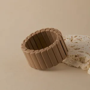 Détail d'un bracelet bohème élastique en résine kaki sur un support en pierre