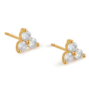 Macro detail of gold-plated clover earrings featuring three sparkling zircon stones