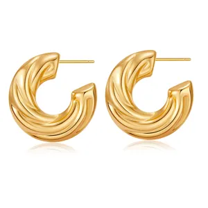 Detail of chunky gold C-shaped earrings with a twisted polished 18K plated surface