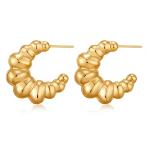 Detailed macro view of gold C-shaped croissant earrings with spiral textured finish