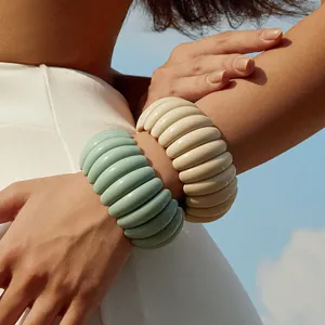 Detail of wide chunky resin bracelets with wave texture in mint and cream colors