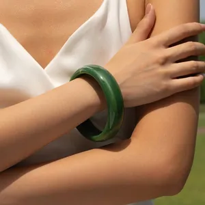 Detailed view of wide green marbled acrylic bangle on model for elegant styling