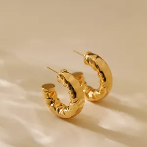 Detailed close-up of C-shaped gold earrings with irregular textured crumpled finish