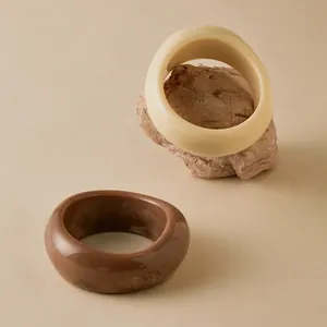 Detailed view of thick acrylic bangles in cream white and marble amber on natural stones