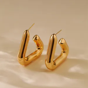 Macro detail of gold U-shaped hoop earrings with a polished mirror finish on a pedestal
