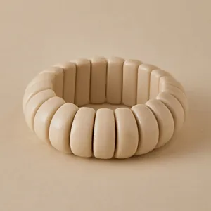 Macro shot of minimalist chunky cream acrylic stretch beaded bracelet with smooth finish
