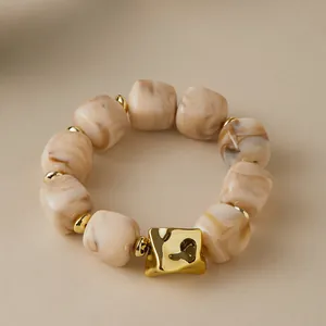 Detail of irregular marble resin links and polished gold metallic accent on chic bracelet