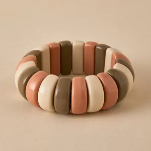 Close-up of chunky earth-tone resin beaded elastic bracelet in cream, red, and olive brown
