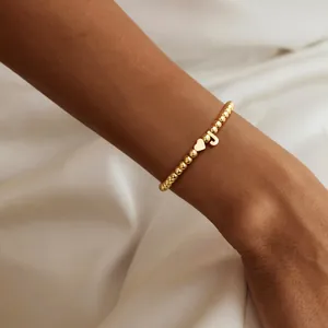 Polished gold beaded bracelet for women featuring heart charm and letter J pendant