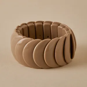 Detailed top view of a chunky khaki elasticated resin bracelet on a warm beige backdrop