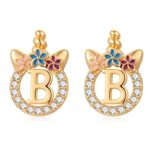 Détail de boucle d'oreille licorne dorée avec lettre B, fleurs et pavé de zircons