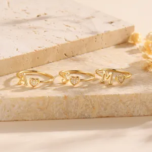 Golden heart ring with initial letters A S M and pavé zircon stones on beige stone