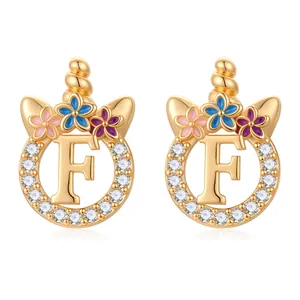 Gros plan de boucles d'oreilles licorne lettre F dorées avec fleurs et zircons