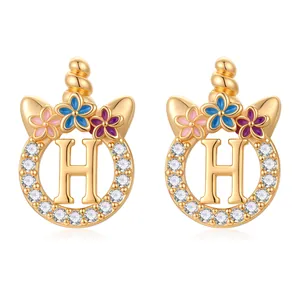 Détail d'une boucle d'oreille licorne dorée avec zircons et fleurs en émail