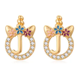 Détail de boucles d'oreilles licorne lettre J dorées avec pierres de zircon