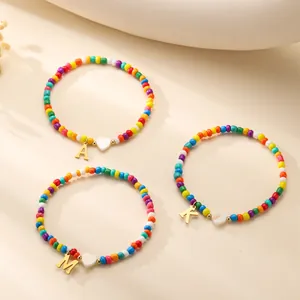 Colorful beaded bracelet with golden letter charms and a white heart pendant detail