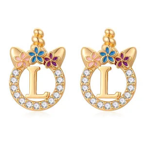 Détail de puce d'oreille licorne dorée avec lettre L, zircons et fleurs en émail