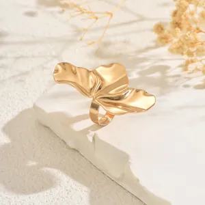 Detailed view of a gold irregular crumpled wing ring on a white stone background