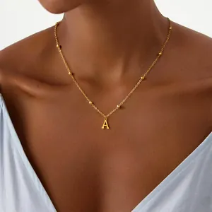 Close-up of golden letter A pendant necklace with beaded chain on a female model