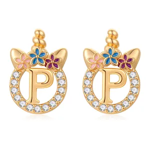 Détail de boucles d'oreilles licorne dorées avec lettre P zircon et fleurs émaillées