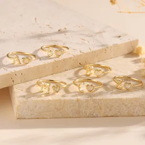Gold letter heart rings with sparkling zircon pavé on an elegant marble surface
