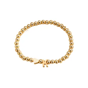 Polished gold beaded bracelet featuring a heart charm and a capital letter K pendant