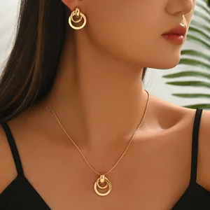 Golden nested triple ring necklace set and earrings on model with polished finish