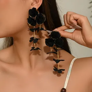Elegant large black chiffon flower drop earrings with golden chains on a female model
