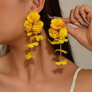 Close-up of bright yellow layered chiffon flower drop earrings on a model