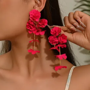 Detail of vivid pink layered chiffon flower earrings with long gold tassel on a model