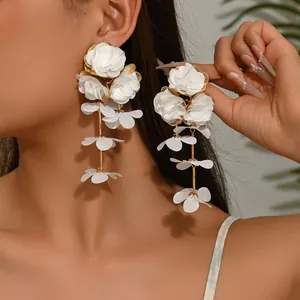 Close-up of elegant long white chiffon flower drop earrings on a model with golden metal stems